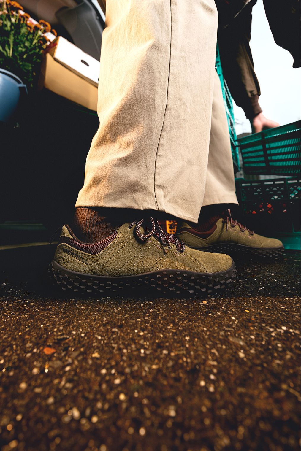 Merrell casual shoes worn with tan trousers at a market.